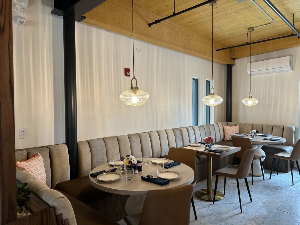 Curved banquette seating and round tables set for service in the Aire dining room