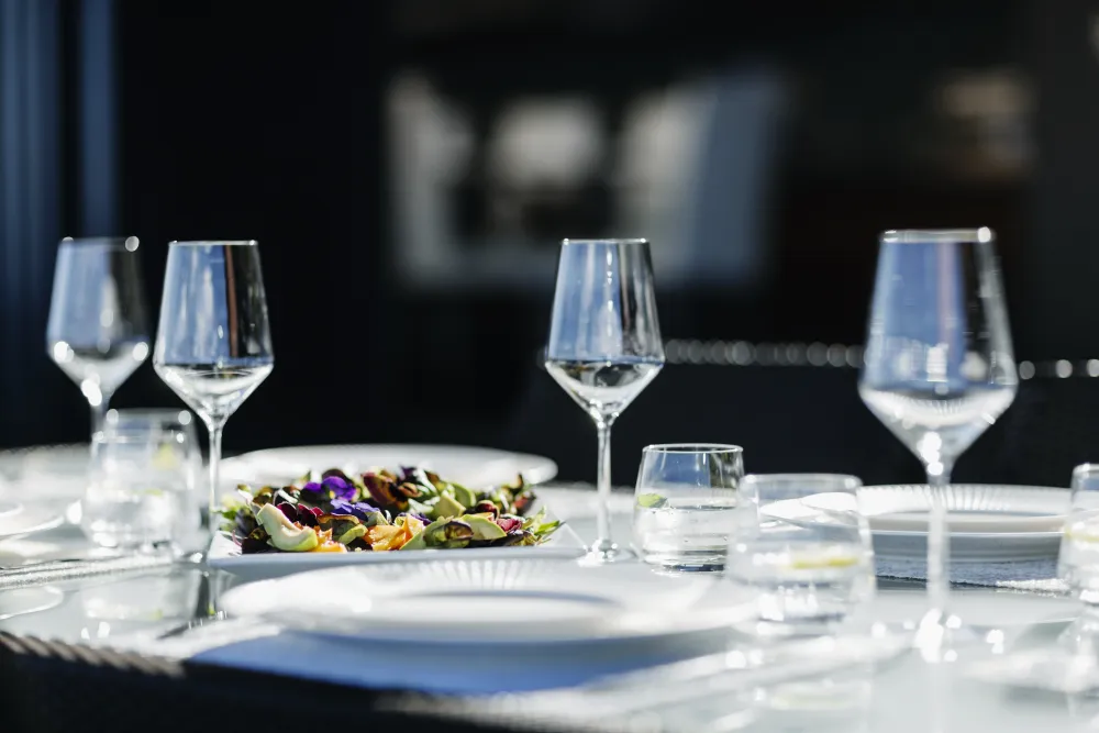 Glass stemware and a plated salad set on a table for an al fresco event