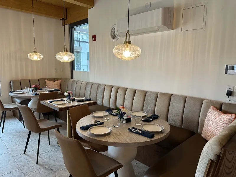 Round table beside a tufted banquette with glass pendant lights