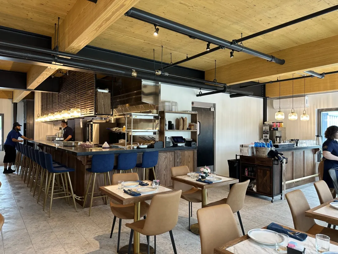 Open kitchen and bar with navy stools under a warm wood ceiling