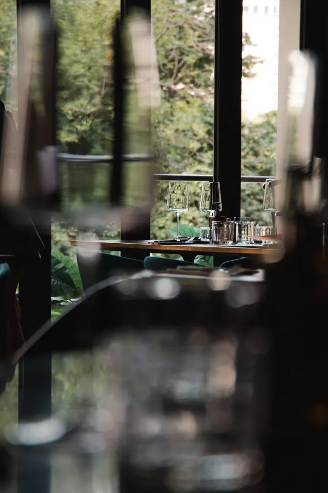 A set table by the window framed by greenery